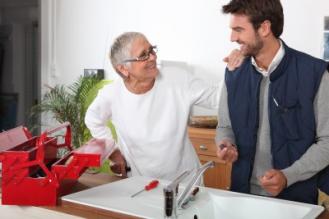 Plumbing contractor in San Jose CA talks with a customer while installing a sink